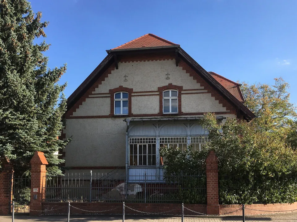 Кованый забор между кирпичными столбами